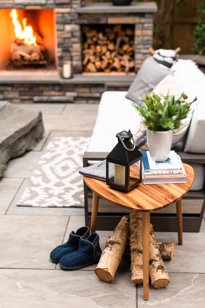Imagen de patio moderno de tamaño medio en patio trasero con chimenea y adoquines de piedra natural