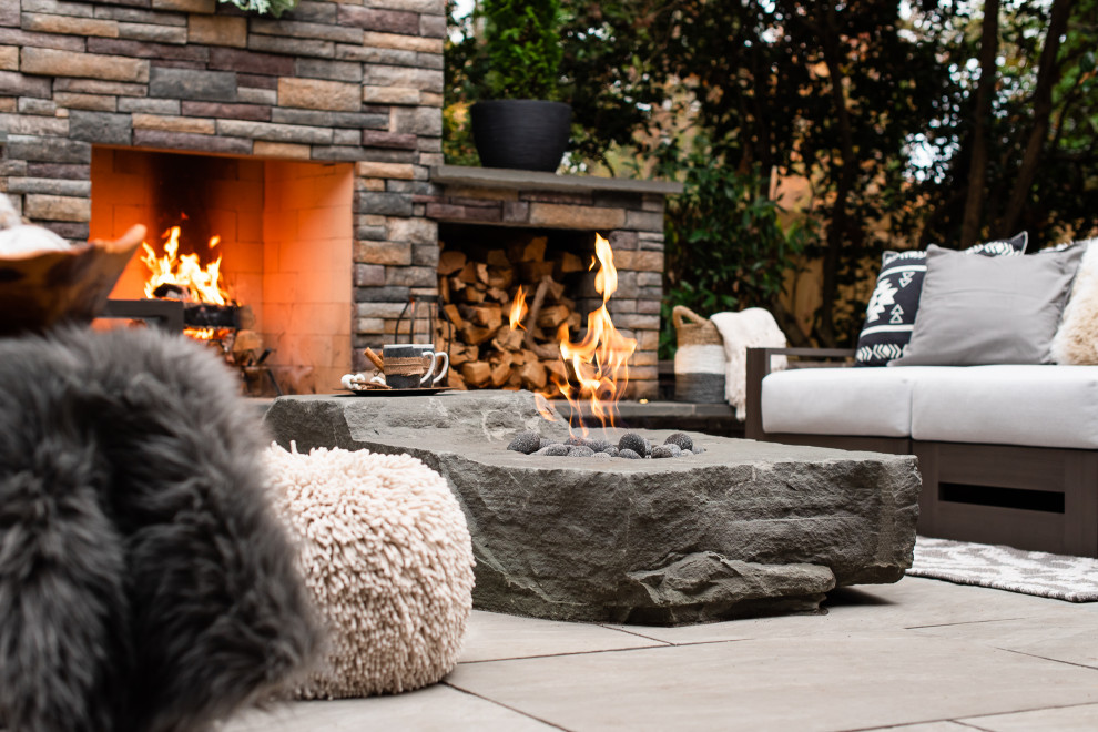 Foto de patio moderno de tamaño medio en patio trasero con chimenea y adoquines de piedra natural