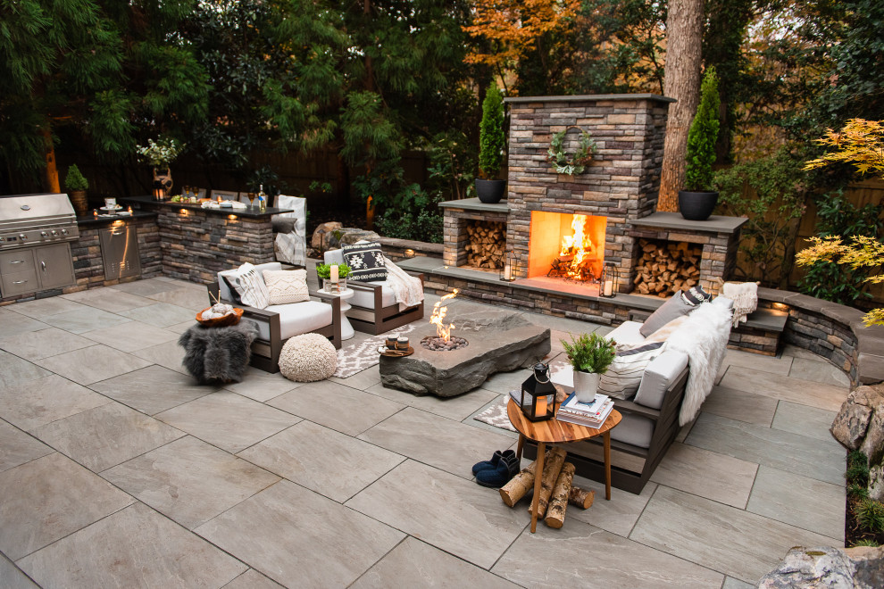 Imagen de patio moderno de tamaño medio en patio trasero con chimenea y adoquines de piedra natural