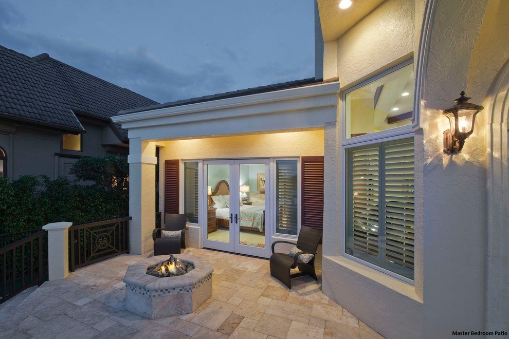 Example of a transitional backyard patio design in Miami with a fire pit