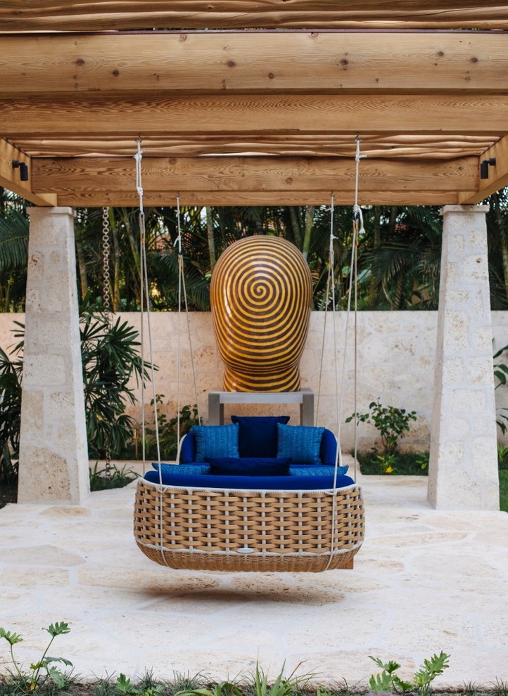 This is an example of a medium sized world-inspired back patio in Hawaii with a pergola and natural stone paving.