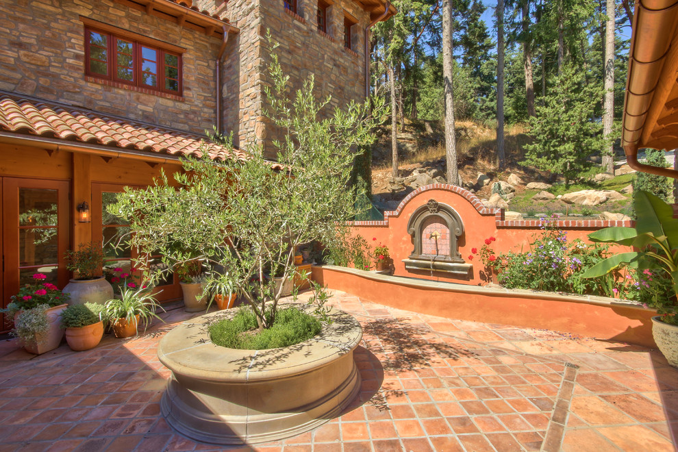 Large tuscan courtyard tile patio photo in Vancouver with no cover