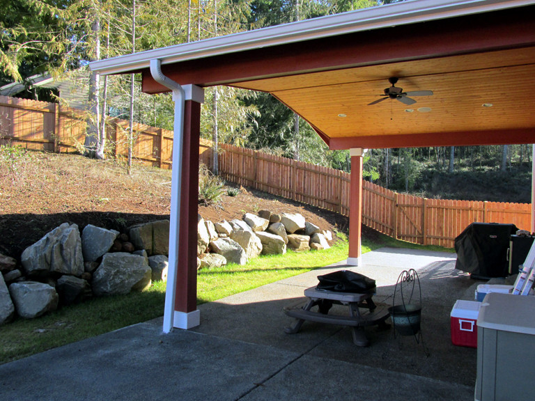Immagine di un patio o portico country di medie dimensioni e dietro casa con lastre di cemento e un tetto a sbalzo
