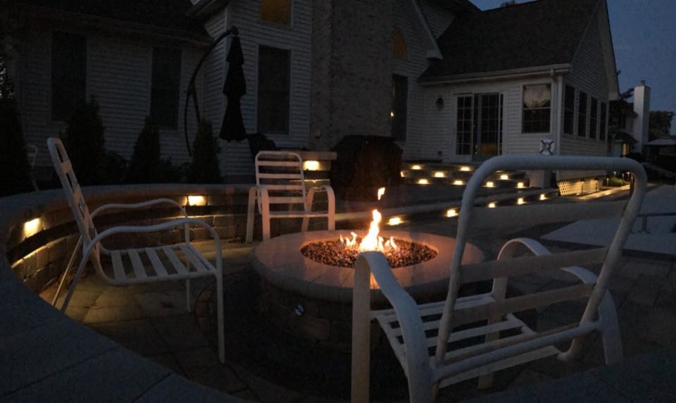 Medium sized contemporary back patio in Chicago with a fire feature and brick paving.