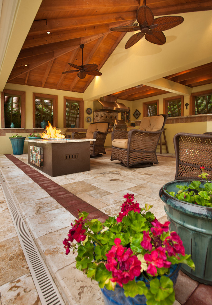 Großer Mediterraner Patio hinter dem Haus mit Outdoor-Küche, Natursteinplatten und Markisen in Tampa