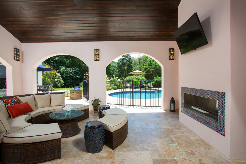 Design ideas for a mediterranean back patio in DC Metro with natural stone paving, a roof extension and a fireplace.