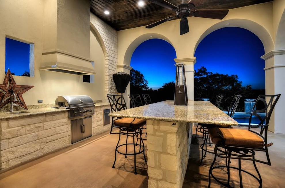 Inspiration for a large mediterranean back patio in Austin with an outdoor kitchen, concrete slabs and a roof extension.
