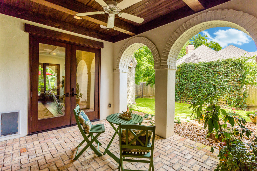 Large mediterranean courtyard patio in Houston with brick paving and a roof extension.