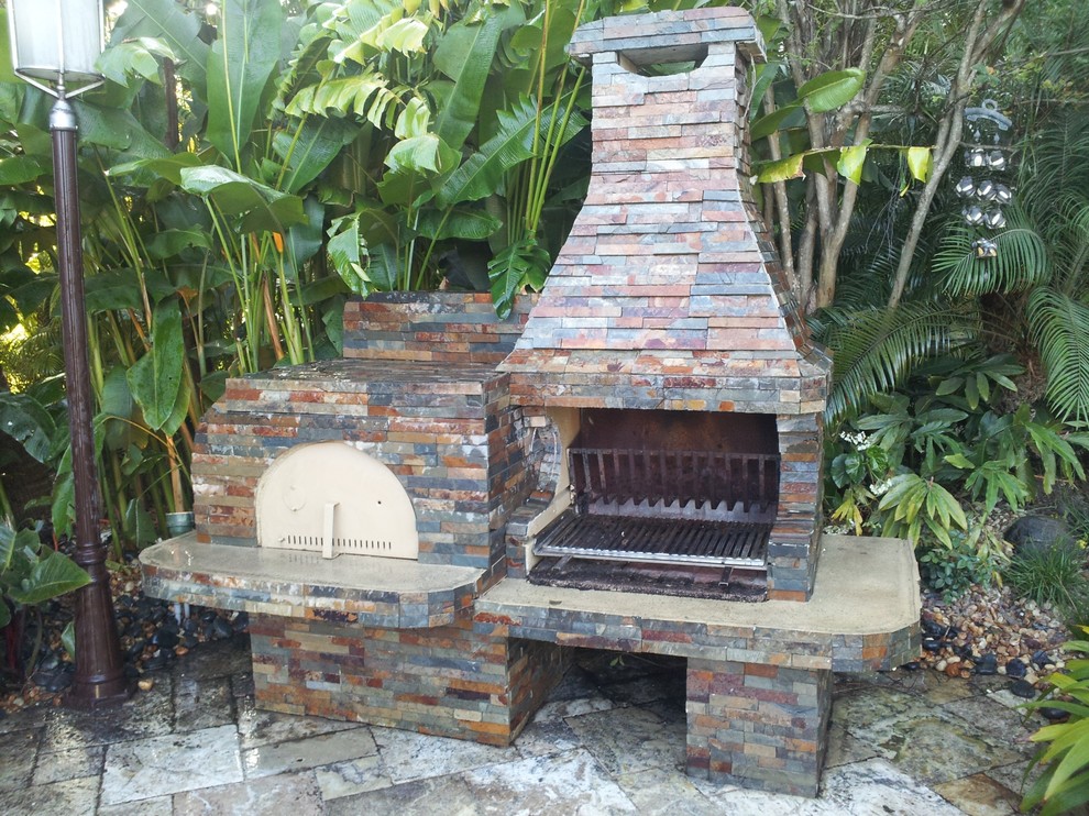 Example of a mid-sized tuscan backyard stone patio kitchen design in Miami with no cover