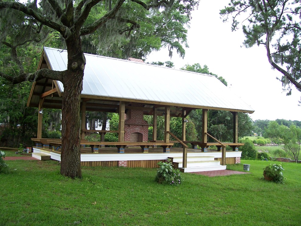 Réalisation d'une terrasse arrière tradition avec un gazebo ou pavillon et un foyer extérieur.