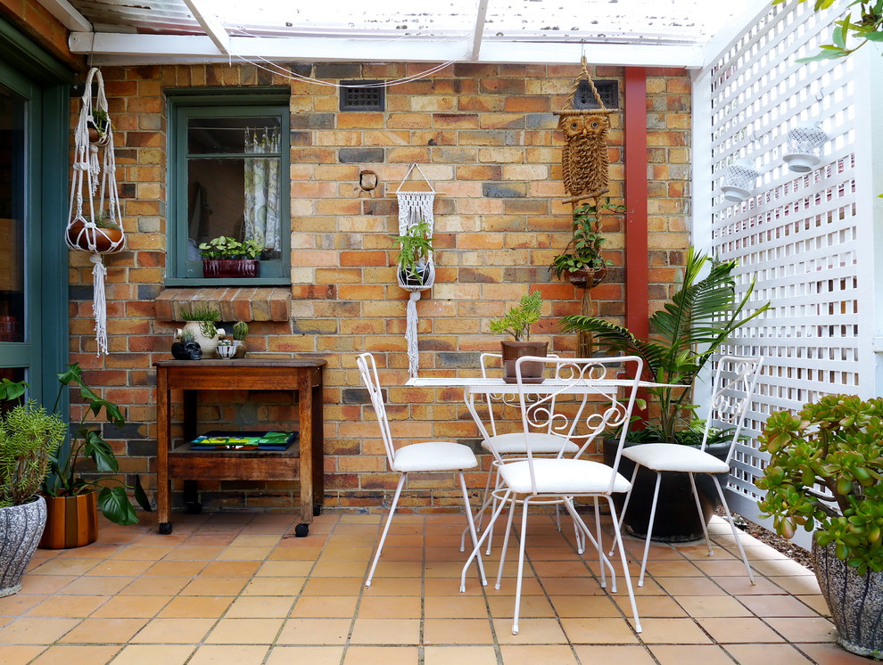 Foto di un patio o portico eclettico di medie dimensioni con un giardino in vaso, piastrelle e una pergola