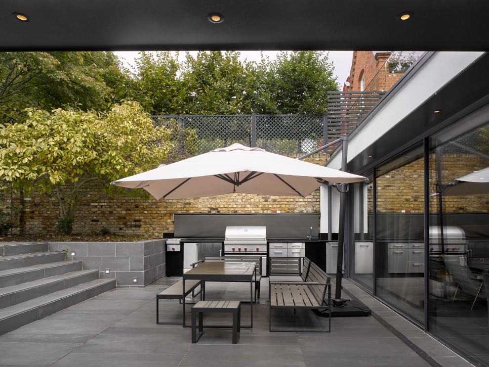 Diseño de patio actual de tamaño medio sin cubierta en patio trasero con cocina exterior y adoquines de hormigón