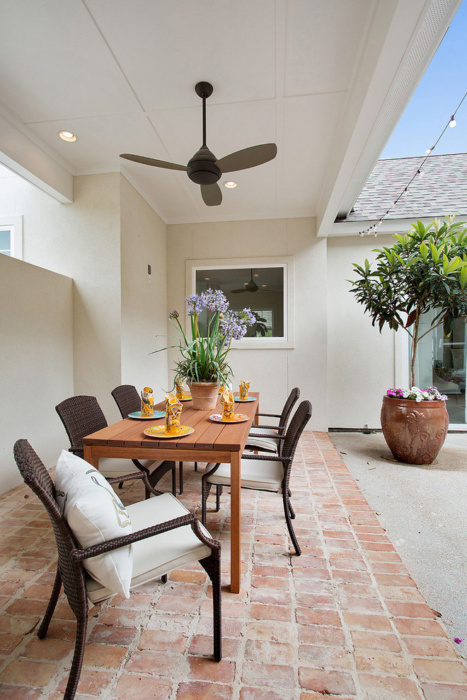 This is an example of a traditional back patio in New Orleans with brick paving and a roof extension.