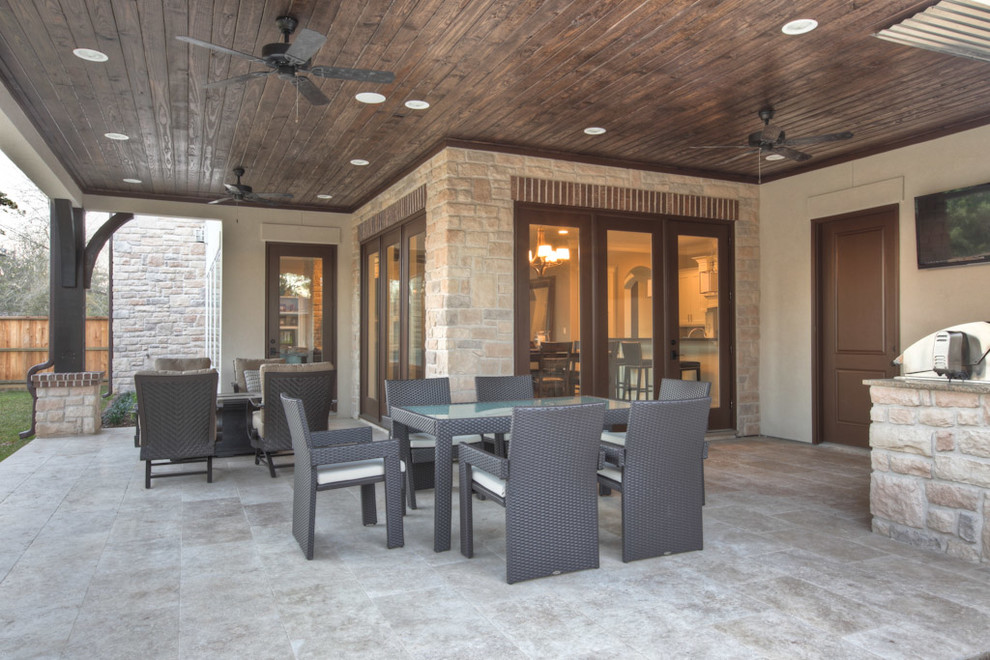 Example of a large classic backyard concrete paver patio kitchen design in Houston with a roof extension