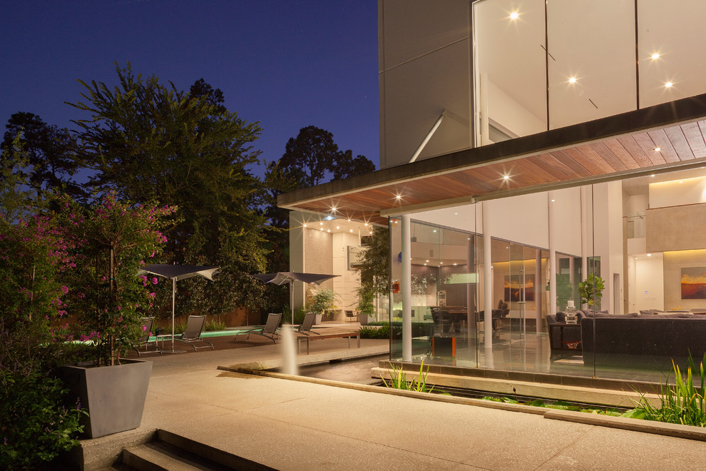 Diseño de patio moderno grande sin cubierta en patio trasero con fuente y adoquines de hormigón