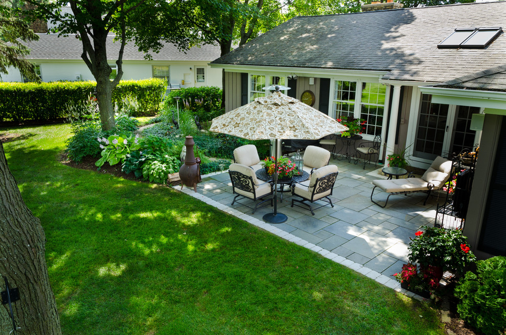 Medium sized classic back patio in Milwaukee with natural stone paving.