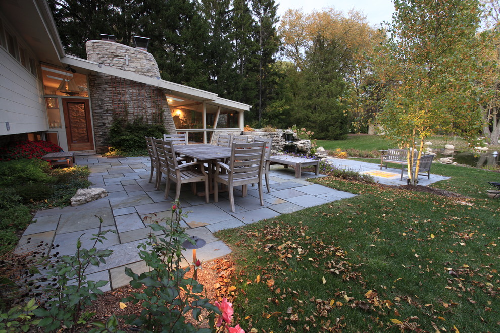Diseño de patio actual grande sin cubierta en patio trasero con fuente y adoquines de piedra natural