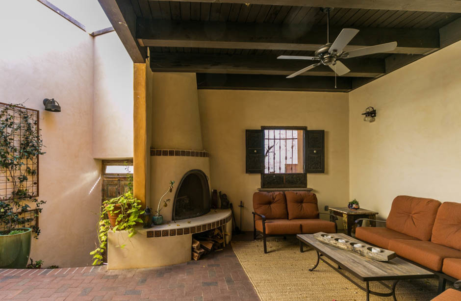 Foto di un patio o portico stile americano con un focolare, pavimentazioni in mattoni e un tetto a sbalzo