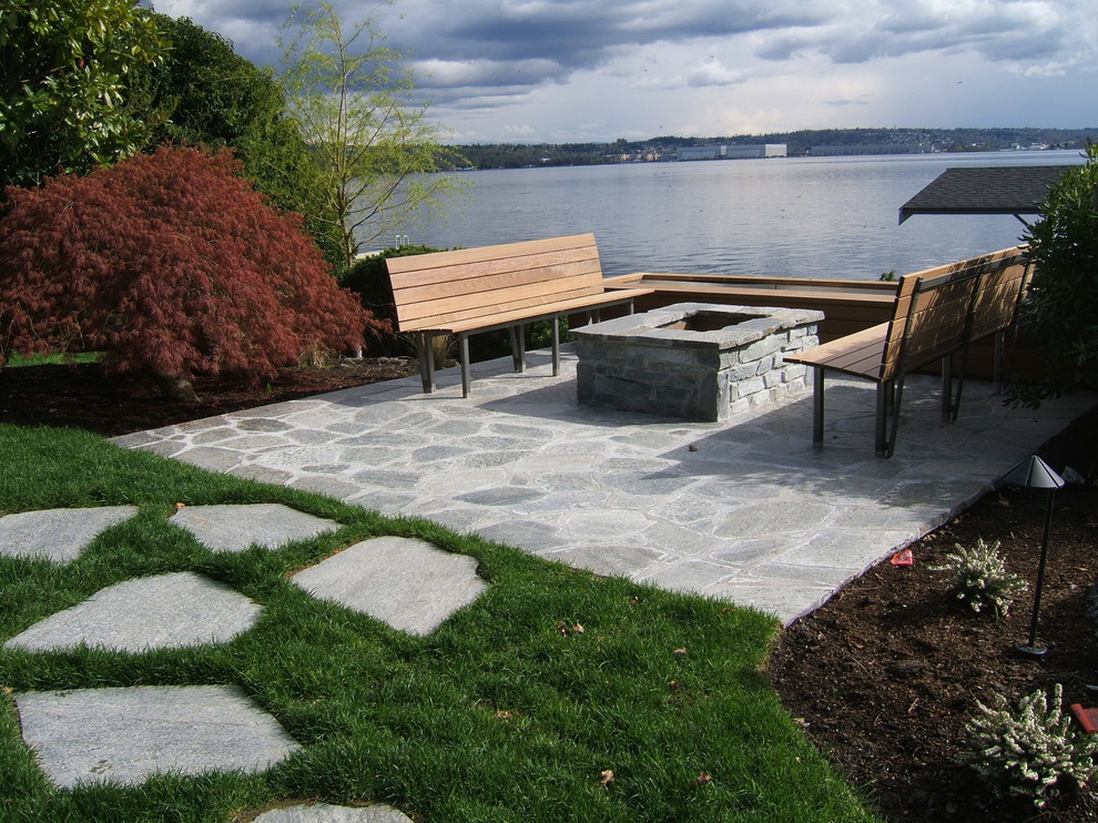 Example of a mid-sized minimalist backyard stone patio design in Seattle with a fire pit