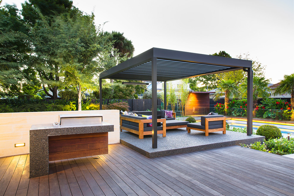 This is an example of a medium sized world-inspired back patio in Christchurch with an outdoor kitchen, concrete slabs and a pergola.