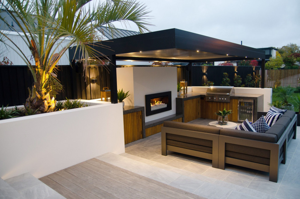 Cette photo montre une grande terrasse latérale moderne avec une cuisine d'été, du carrelage et une pergola.