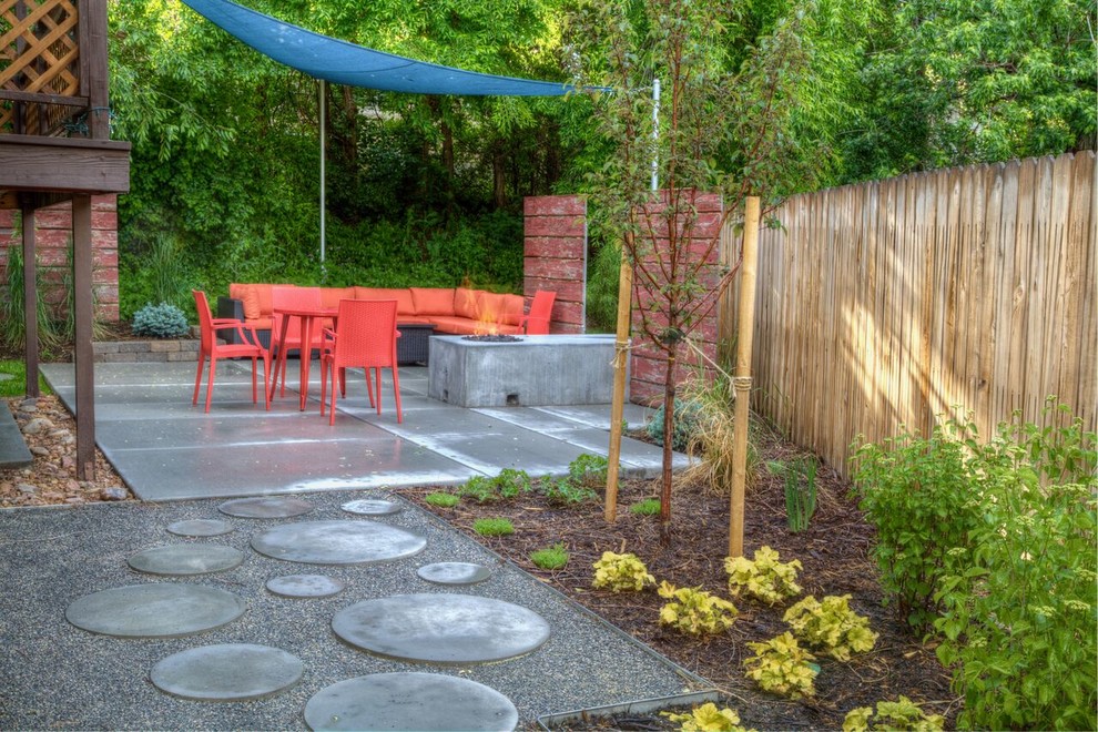Esempio di un patio o portico moderno di medie dimensioni e dietro casa con un focolare, lastre di cemento e un parasole