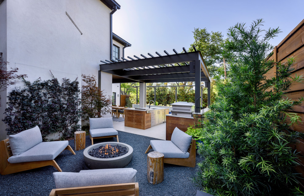 Idée de décoration pour une terrasse arrière design de taille moyenne avec un foyer extérieur et une pergola.