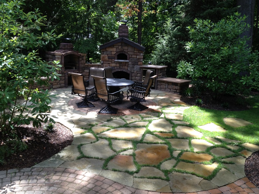 Foto de patio clásico de tamaño medio en patio trasero con chimenea y adoquines de piedra natural