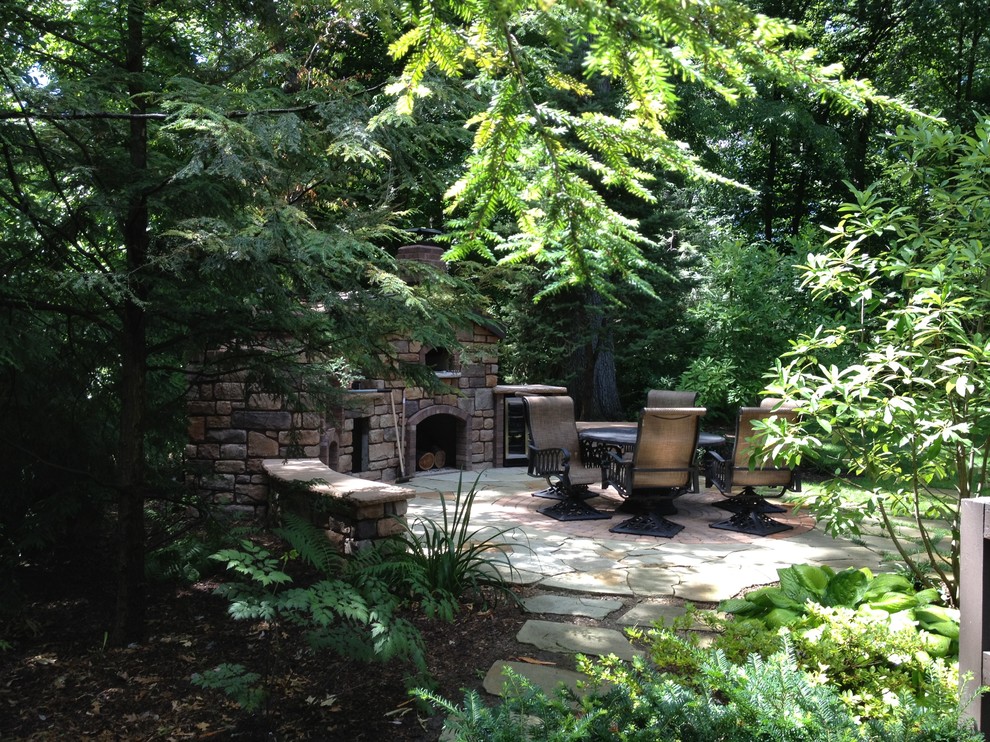 Immagine di un patio o portico chic di medie dimensioni e dietro casa con un caminetto e pavimentazioni in pietra naturale