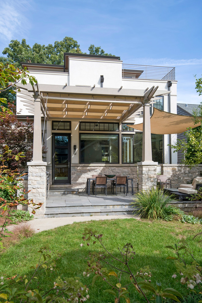 Midcentury back patio in Chicago with natural stone paving and a pergola.