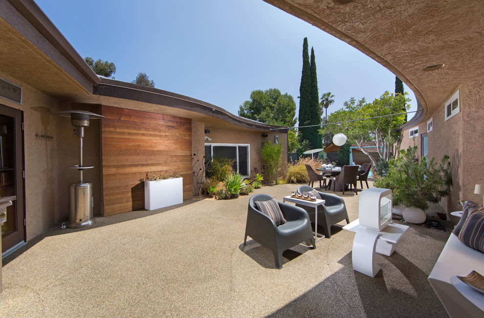 Foto di un grande patio o portico moderno dietro casa con un focolare, lastre di cemento e un tetto a sbalzo