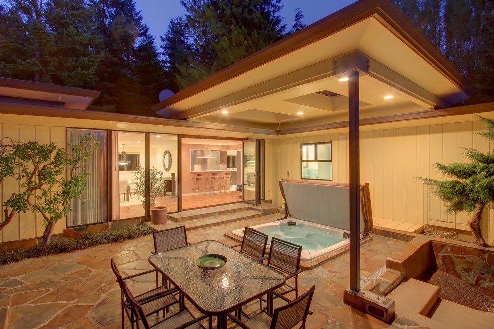 Ispirazione per un patio o portico minimalista dietro casa con pavimentazioni in pietra naturale e un tetto a sbalzo