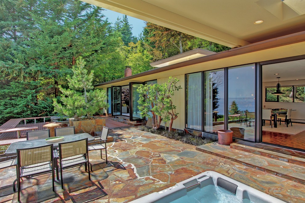 Inspiration for a 1960s stone patio remodel in Seattle with a roof extension