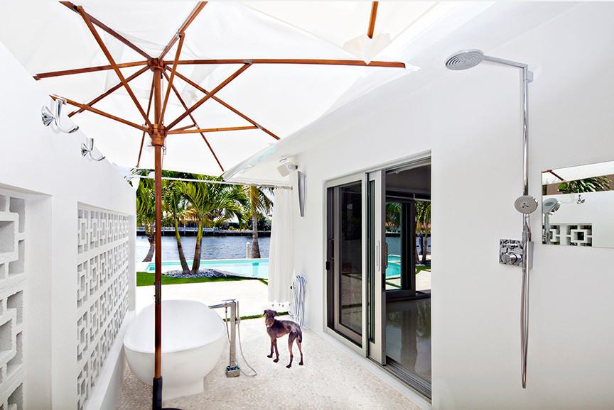 Photo of a medium sized midcentury back patio in Miami with an outdoor shower, natural stone paving and an awning.