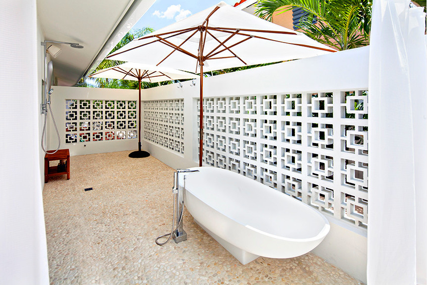 Medium sized midcentury back patio in Miami with an outdoor shower, natural stone paving and an awning.