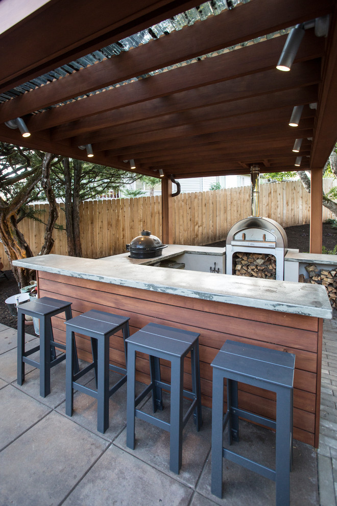 Cette photo montre une très grande terrasse arrière rétro avec une cuisine d'été, des pavés en béton et une pergola.
