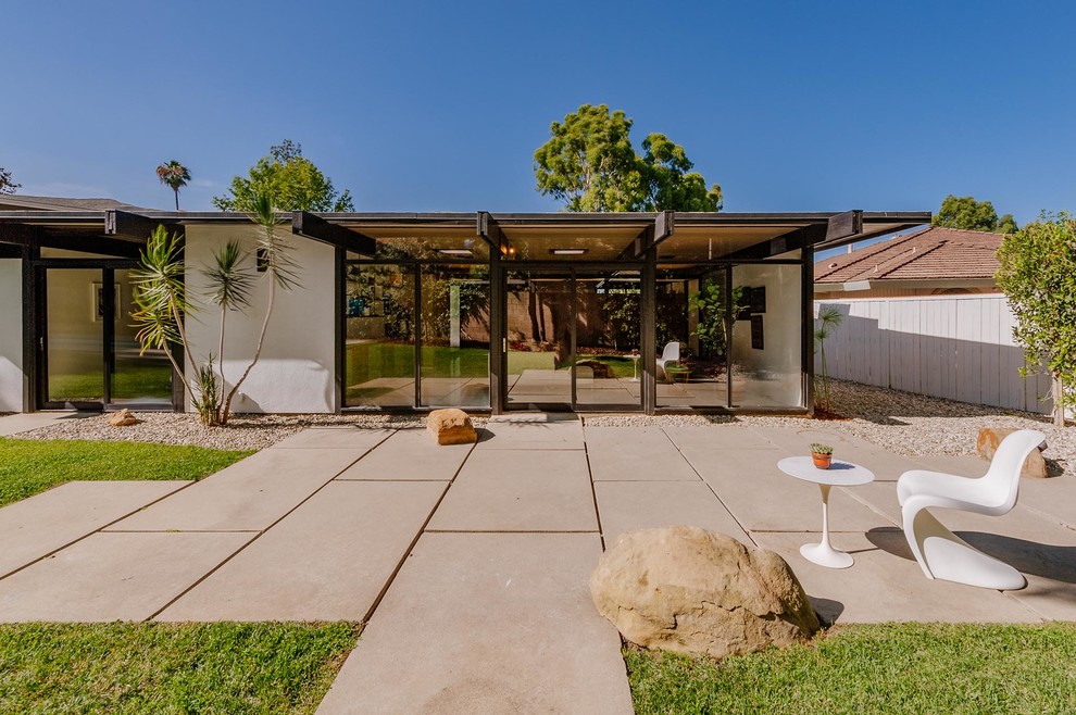 This is an example of a medium sized midcentury back patio in Los Angeles with stamped concrete.