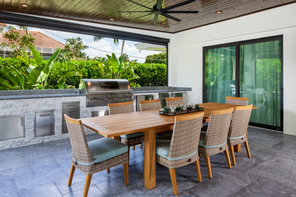 Example of a large 1950s backyard stone patio kitchen design in Miami with a roof extension