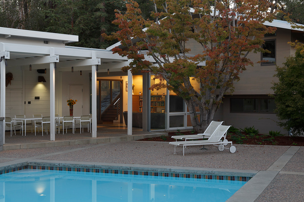 This is an example of a large retro back patio in San Francisco with concrete slabs and a roof extension.