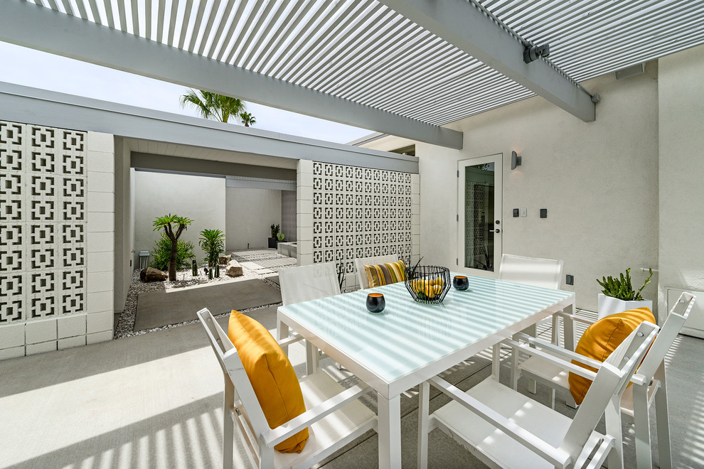 This is an example of a retro patio in Los Angeles with concrete slabs and a pergola.