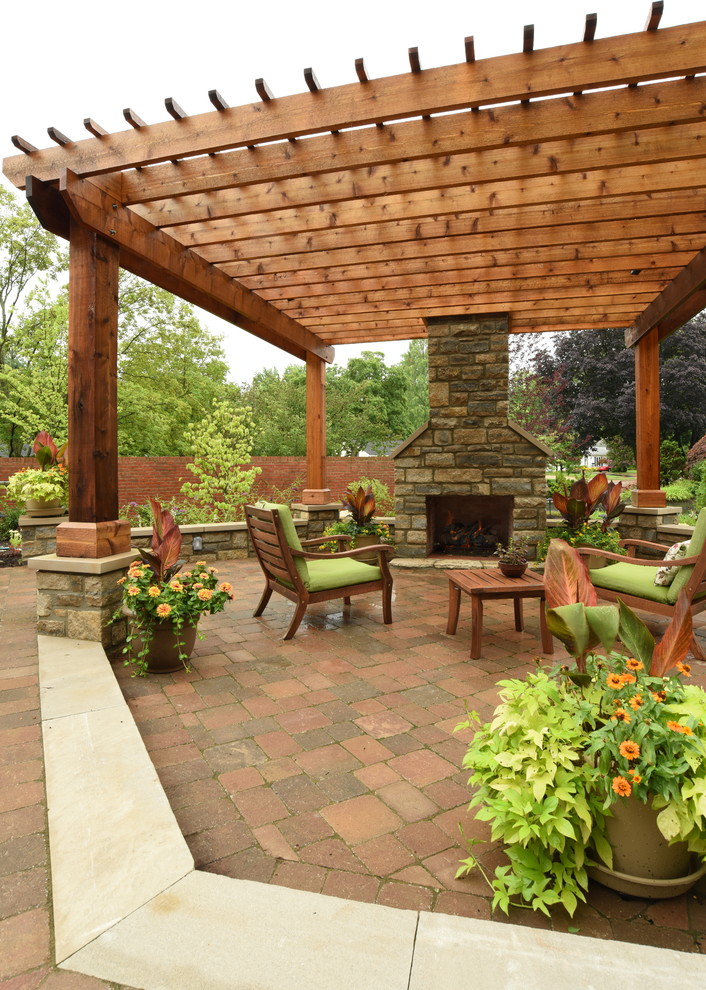 This is an example of a large traditional back patio in Columbus with brick paving and a pergola.