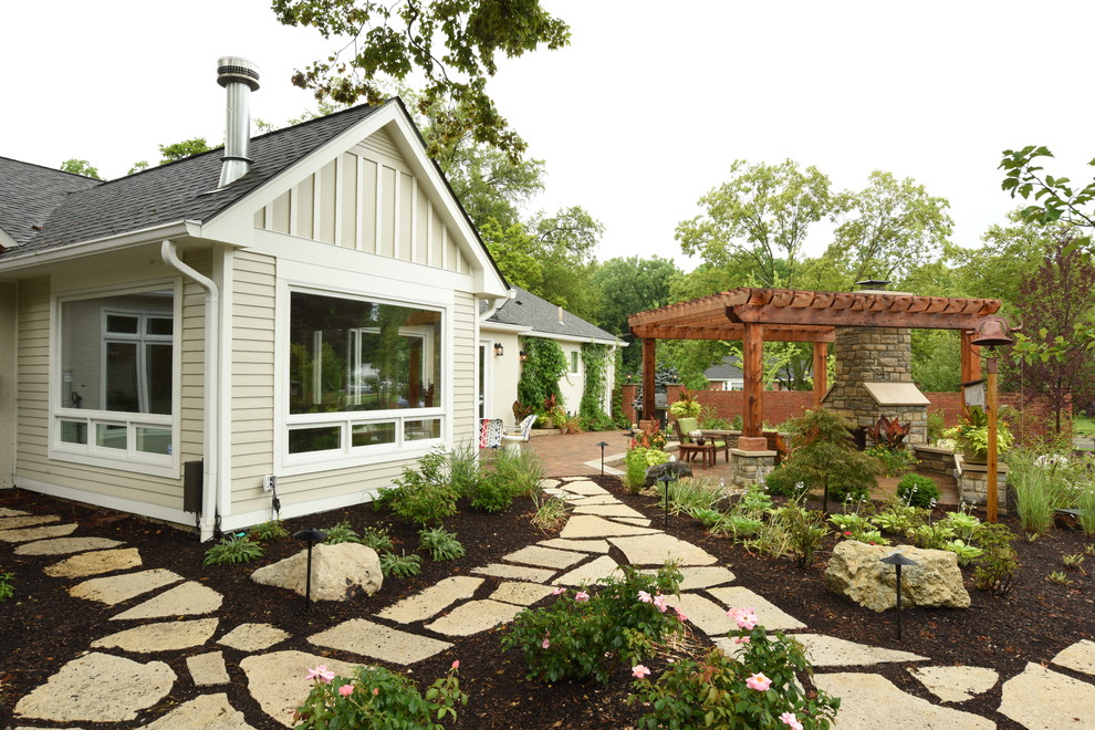 Large transitional backyard stone patio photo in Columbus with a pergola