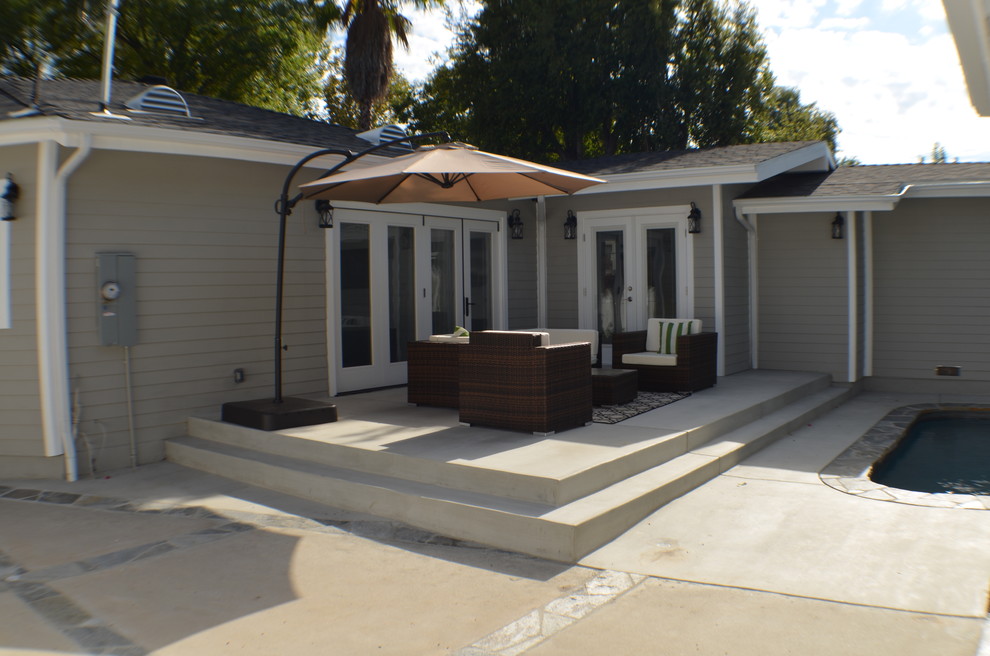 Esempio di un patio o portico chic di medie dimensioni e dietro casa con lastre di cemento e un parasole