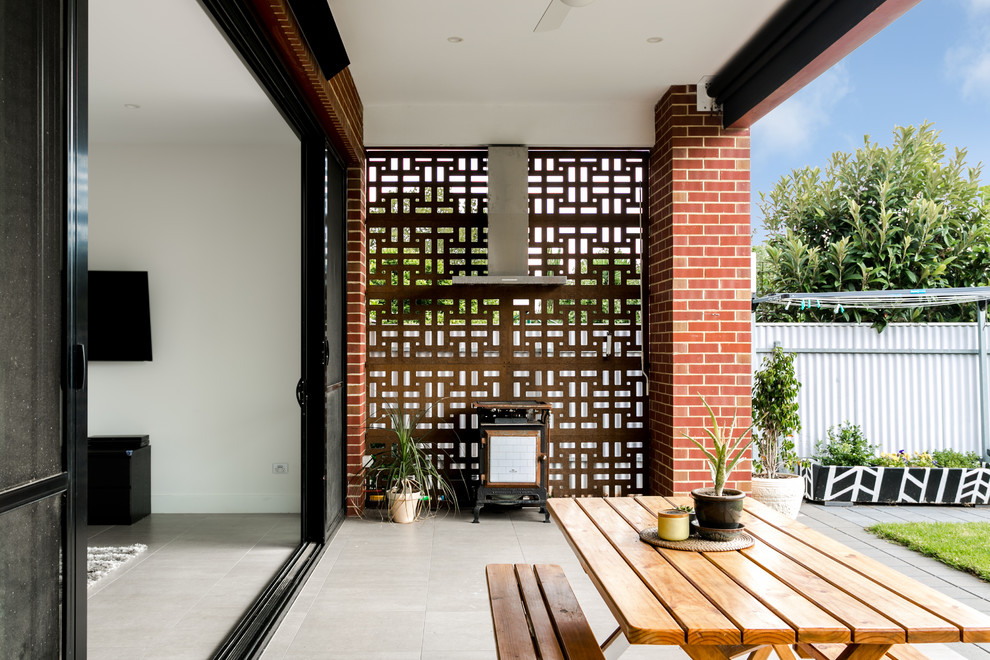 Aménagement d'une terrasse arrière contemporaine avec une cuisine d'été, des pavés en béton et une extension de toiture.