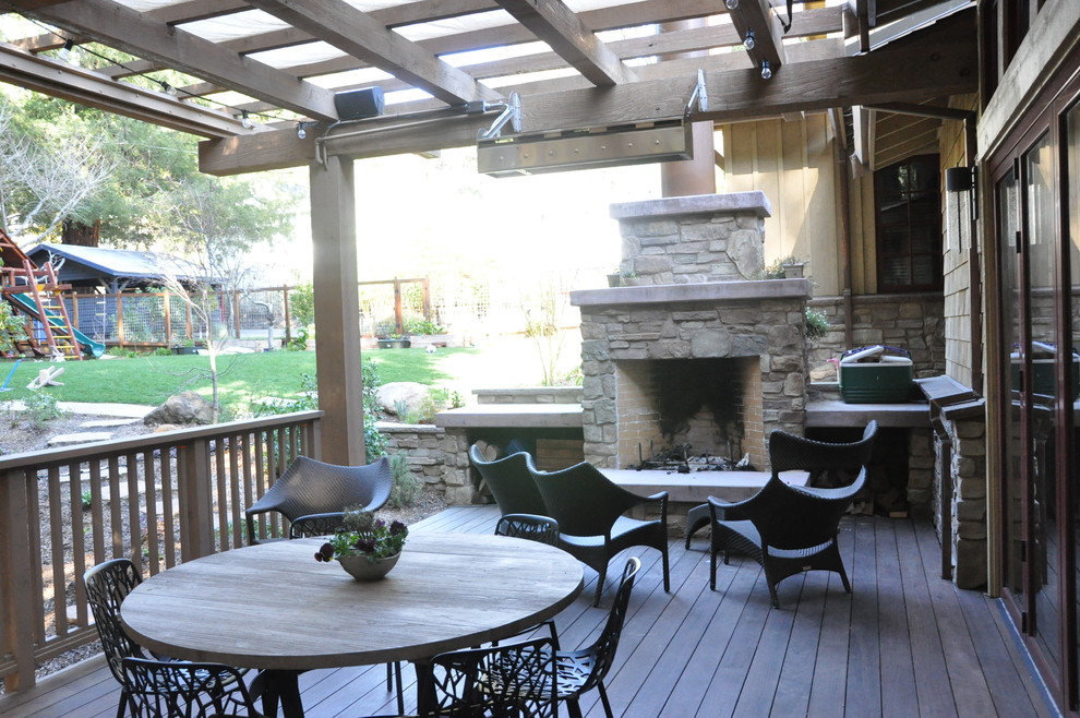 This is an example of a large rustic front patio in San Francisco with decking, a pergola and a fireplace.