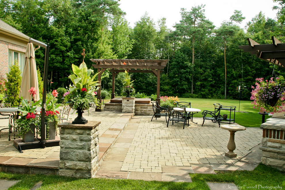 Ejemplo de patio clásico grande en patio trasero con fuente, adoquines de piedra natural y pérgola