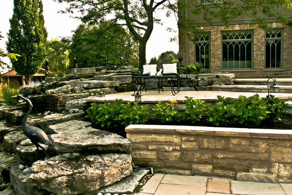 Immagine di un grande patio o portico tradizionale dietro casa con fontane, pavimentazioni in pietra naturale e nessuna copertura