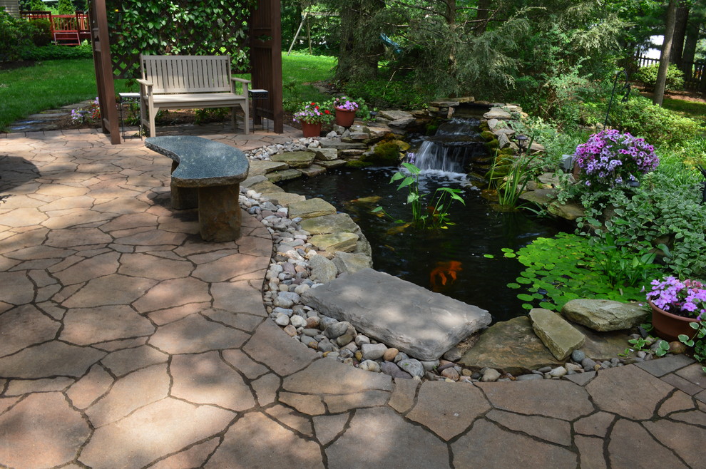 Inspiration for a mid-sized backyard concrete paver patio fountain remodel in DC Metro with a pergola