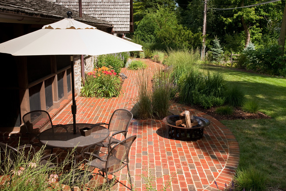 Inspiration for a mid-sized eclectic backyard brick patio remodel in Milwaukee with a fire pit