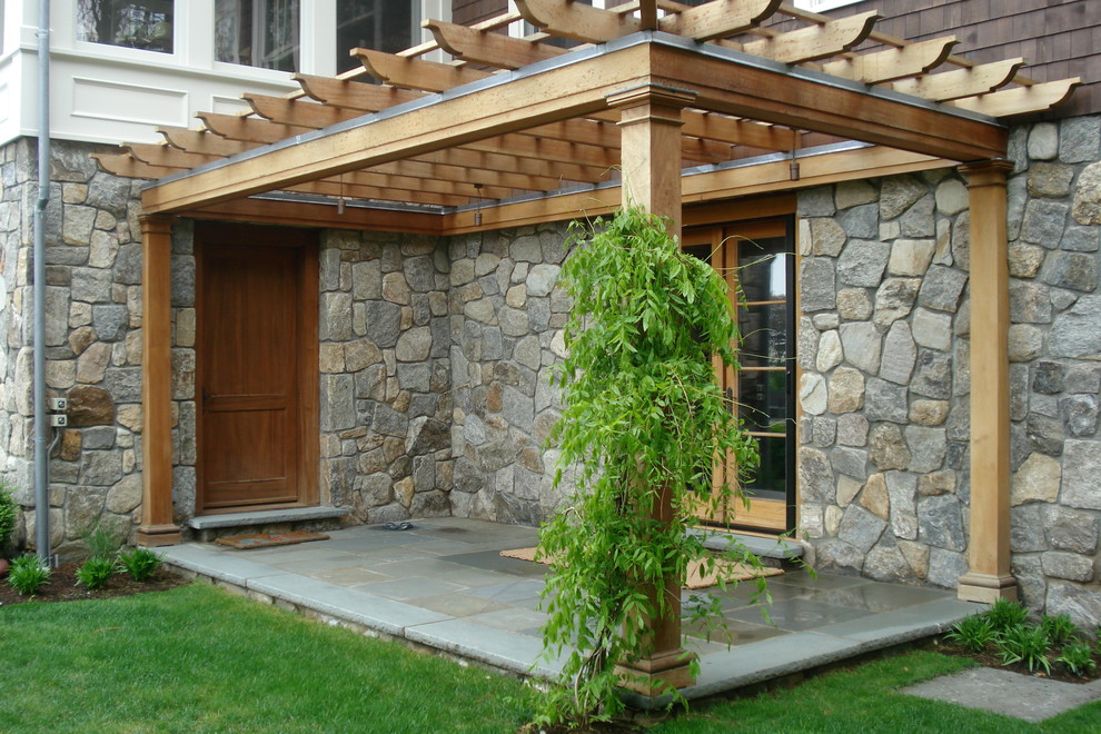 Exempel på en stor modern uteplats på baksidan av huset, med naturstensplattor, en öppen spis och en pergola